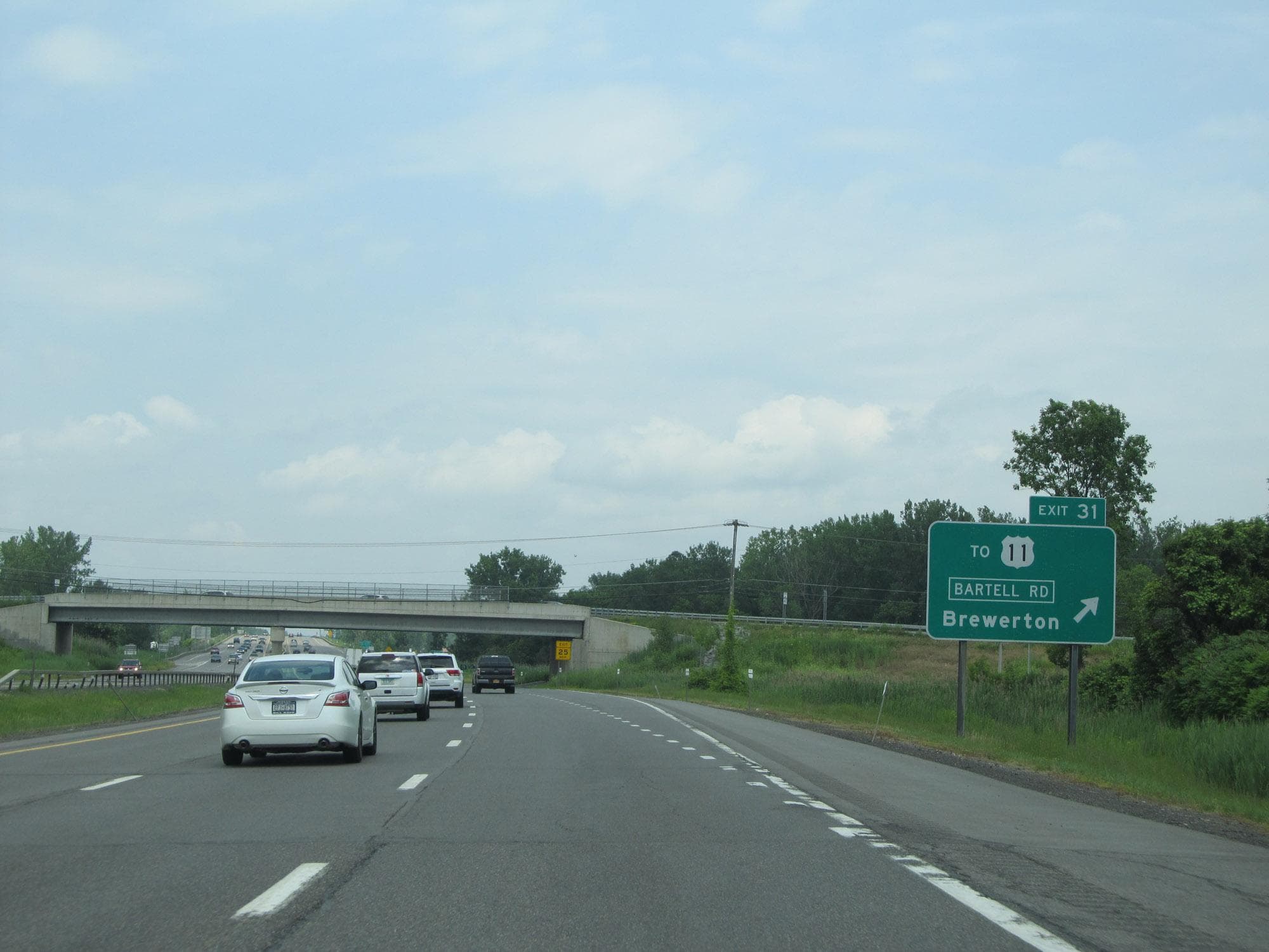Traffic on Interstate 81 approaching an overpass, with a green sign reading Exit 31, To US 11, Bartell Road, Brewerton.